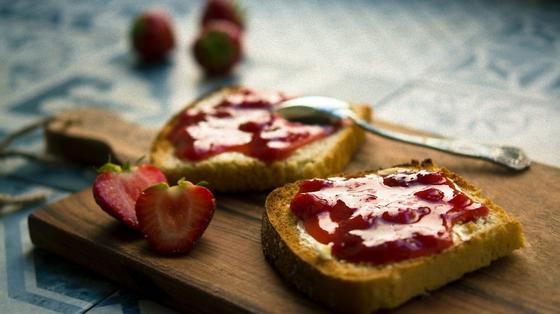 Куски хлеба с клубничным вареньем лежат на деревянной дощечке Куски хлеба с клубничным вареньем лежат на деревянной дощечке