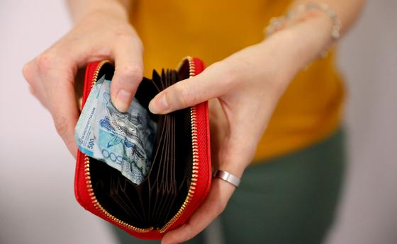 Девушка достает из кошелька помятую банкноту Девушка достает из кошелька помятую банкноту