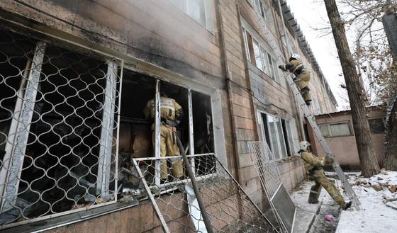 Пожарный стоит в окне здания Пожарный стоит в окне здания