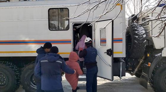 Спасатели заводят людей в служебную машину Спасатели заводят людей в служебную машину