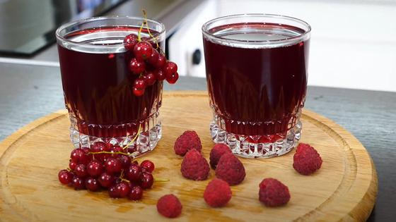 Красный компот в стаканах и ягоды на столе Красный компот в стаканах и ягоды на столе