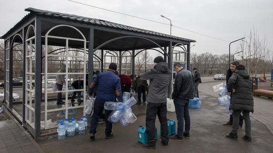 Мужчины идут с бутылками к колонке Мужчины идут с бутылками к колонке