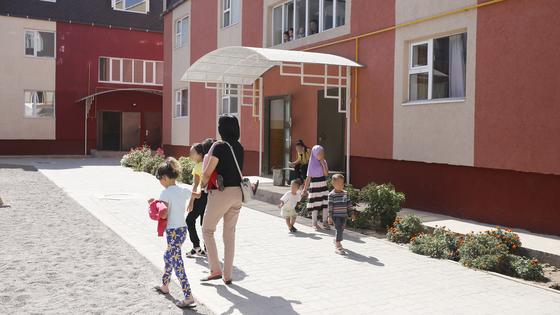 Женщина с детьми идет возле дома Женщина с детьми идет возле дома