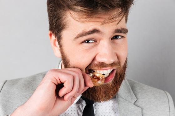 Мужчина кусает золотую монету Мужчина кусает золотую монету