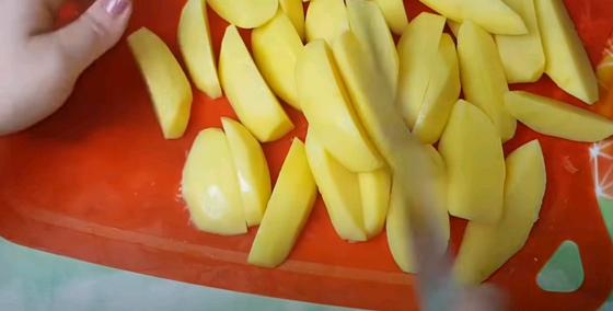 Женщина нарезает картофель для жаркого дольками Женщина нарезает картофель для жаркого дольками