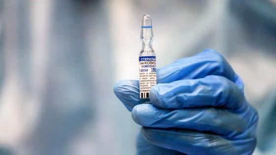 Медработник держит в руках ампулу с вакциной Медработник держит в руках ампулу с вакциной