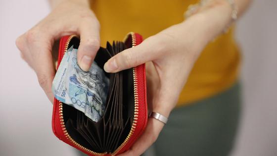 Девушка держит красный кошелек с деньгами Девушка держит красный кошелек с деньгами
