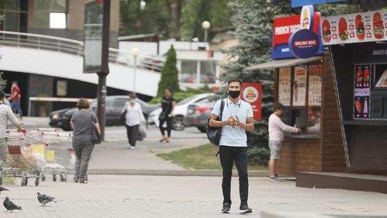 Мужчина в маске идет по улице Алматы Мужчина в маске идет по улице Алматы