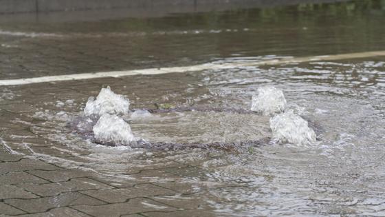 Вода вырывается из-под канализационного люка Вода вырывается из-под канализационного люка