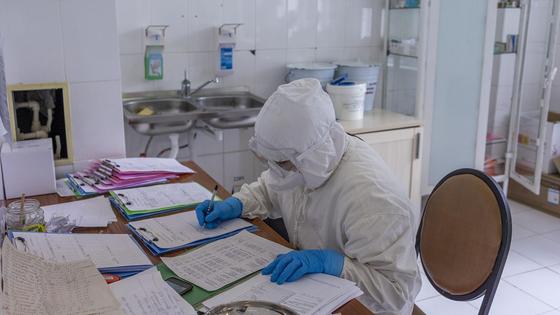 Врач заполняет бумаги за столом Врач заполняет бумаги за столом