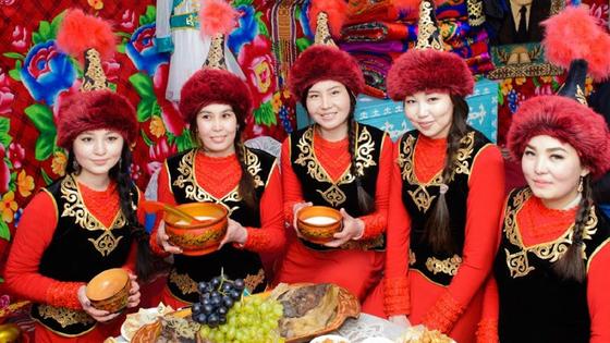 Девушки в национальных костюмах сидят за столом Девушки в национальных костюмах сидят за столом