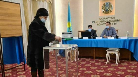 Женщина опускает бюллетень в урну Женщина опускает бюллетень в урну