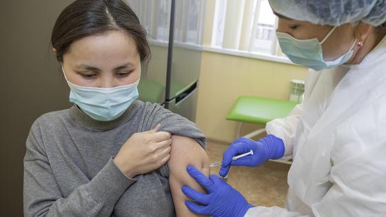 Врач делает прививку девушке в серой кофте Врач делает прививку девушке в серой кофте