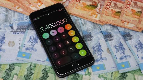 Телефон с открытым калькулятором лежит на деньгах Телефон с открытым калькулятором лежит на деньгах