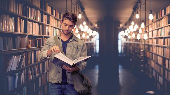 Парень в библиотеке читает книгу Парень в библиотеке читает книгу