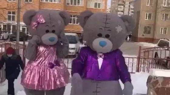 Люди в костюмах мишек Тедди идут по улице Люди в костюмах мишек Тедди идут по улице