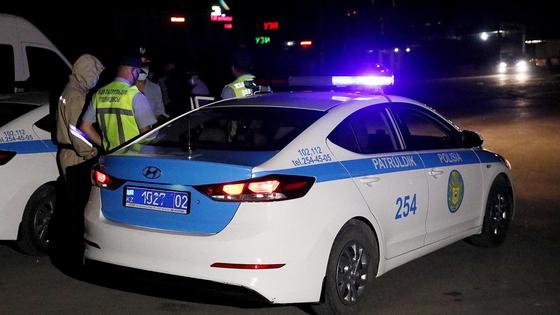 Полицейские стоят рядом со служебным авто с включенными мигалками Полицейские стоят рядом со служебным авто с включенными мигалками