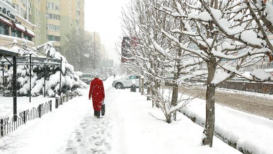 Женщина в красной одежде идет по заснеженной улице Женщина в красной одежде идет по заснеженной улице
