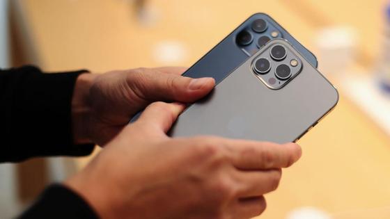 Мужчина держит в руках два iPhone 12 Pro Мужчина держит в руках два iPhone 12 Pro