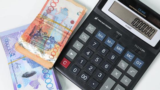 Пачки денег лежат рядом с калькулятором Пачки денег лежат рядом с калькулятором
