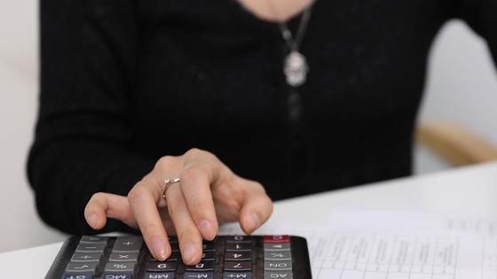 Женщина считает деньги с помощью калькулятора Женщина считает деньги с помощью калькулятора