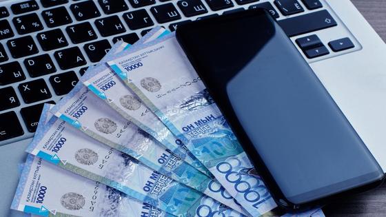 Деньги лежат на нотбуке рядом с телефоном Деньги лежат на нотбуке рядом с телефоном