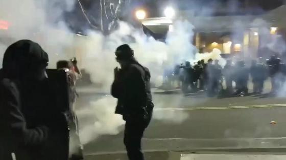 Две группы людей стоят друг напротив друга в дыму на улице Две группы людей стоят друг напротив друга в дыму на улице