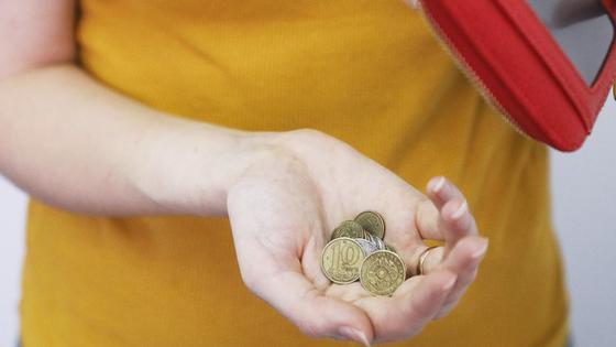 Женщина держит тенге в руке Женщина держит тенге в руке