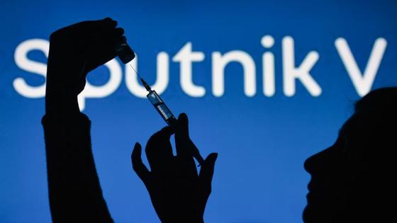 Женщина держит шприц с ампулой на фоне логотипа вакцины Sputnik V Женщина держит шприц с ампулой на фоне логотипа вакцины Sputnik V