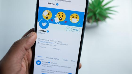 Рука держит телефон с открытым приложением Twitter Рука держит телефон с открытым приложением Twitter