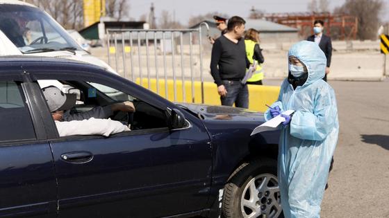 Девушка в костюме санитара подходит к машине Девушка в костюме санитара подходит к машине