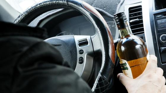 Мужчина сидит за рулем авто и держит бутылку Мужчина сидит за рулем авто и держит бутылку