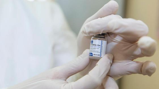 Медработник держит в руках ампулу с вакциной Медработник держит в руках ампулу с вакциной