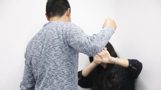 Мужчина заносит кулак над девушкой, пытающейся от него закрыться Мужчина заносит кулак над девушкой, пытающейся от него закрыться