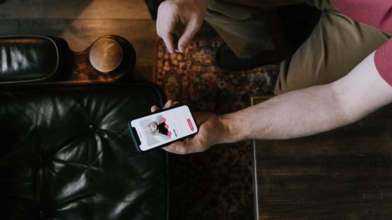 Мужчина держит смартфон с Tinder Мужчина держит смартфон с Tinder