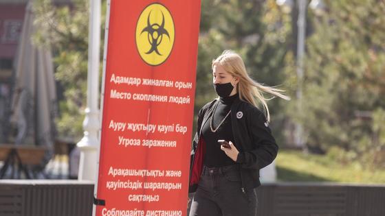 Девушка в маске идет по тротуару Девушка в маске идет по тротуару