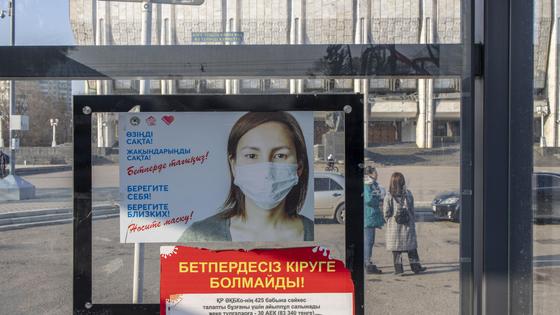 баннер с девушкой в маске висит на улице в Алматы баннер с девушкой в маске висит на улице в Алматы