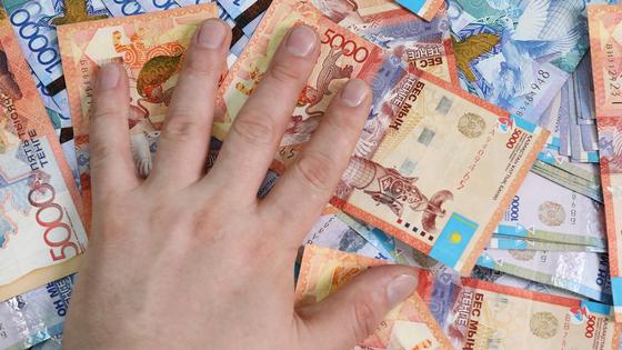 рука лежит на купюрах тенге рука лежит на купюрах тенге