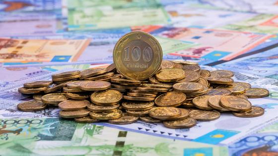 Груда монет лежит на купюрах тенге Груда монет лежит на купюрах тенге