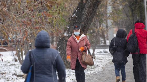 Люди в масках и теплой одежде идут по улице Люди в масках и теплой одежде идут по улице