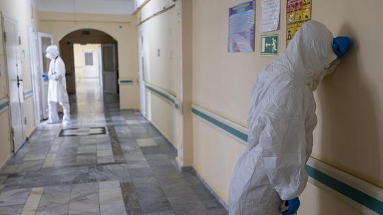 Врач в СИЗ стоит у стены Врач в СИЗ стоит у стены