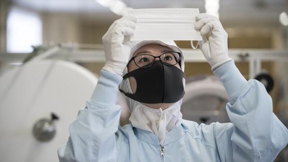 Девушка смотрит на медицинскую маску Девушка смотрит на медицинскую маску
