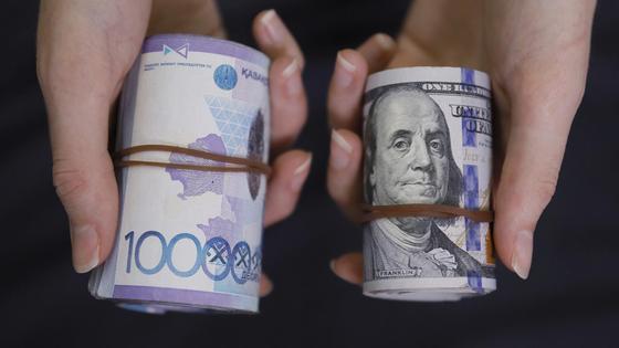 Девушка держит в руках пачку долларов и пачку тенге Девушка держит в руках пачку долларов и пачку тенге