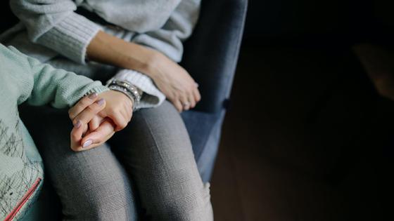 Женщина сидит на кресле и держит руку ребенка Женщина сидит на кресле и держит руку ребенка