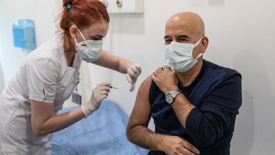 Врач делает укол мужчине в плечо Врач делает укол мужчине в плечо