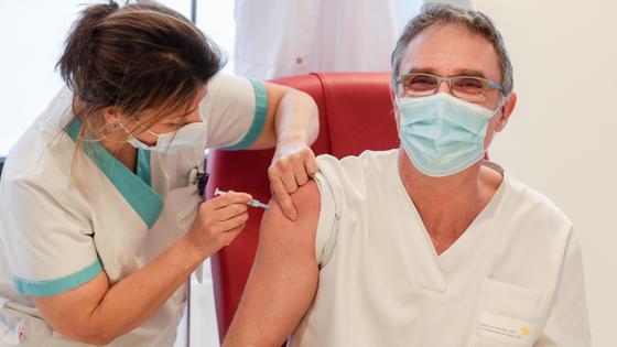 Врач делает прививку мужчине в очках Врач делает прививку мужчине в очках