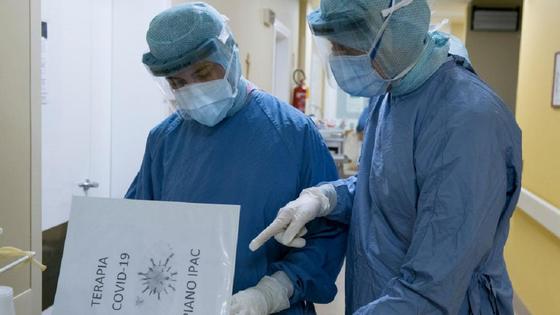Врачи а защитных костюмах читают прокол лечения Врачи а защитных костюмах читают прокол лечения