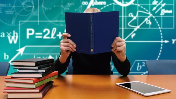 Учитель сидит с книгой за столом Учитель сидит с книгой за столом