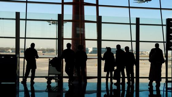 Люди в аэропорту стоят у окна Люди в аэропорту стоят у окна