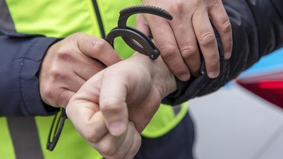 Полицейский одевает наручники на задержанного Полицейский одевает наручники на задержанного